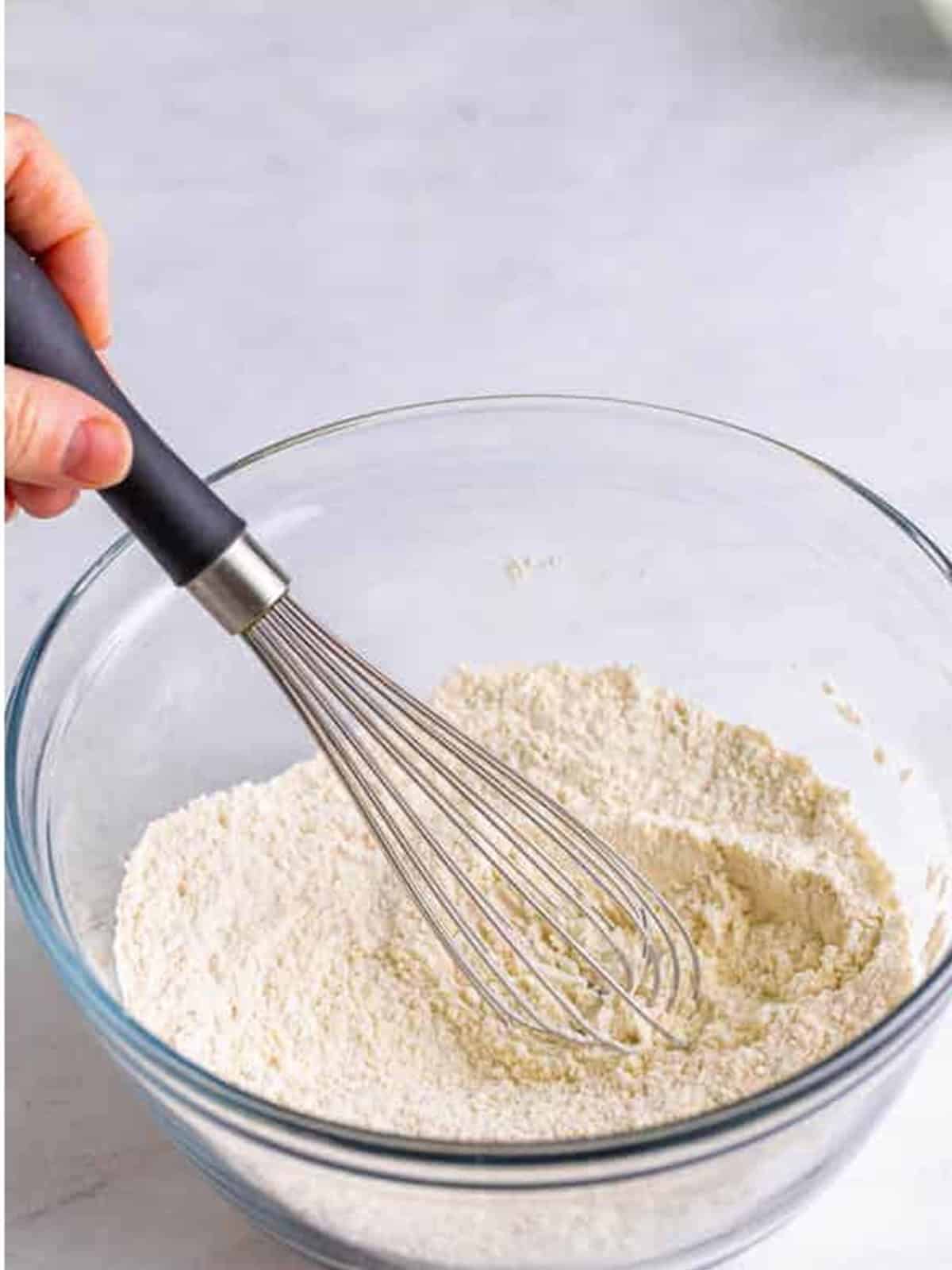 Flour, baking powder, garlic powder, and onion powder whisked together in a bowl for cheese curd batter.