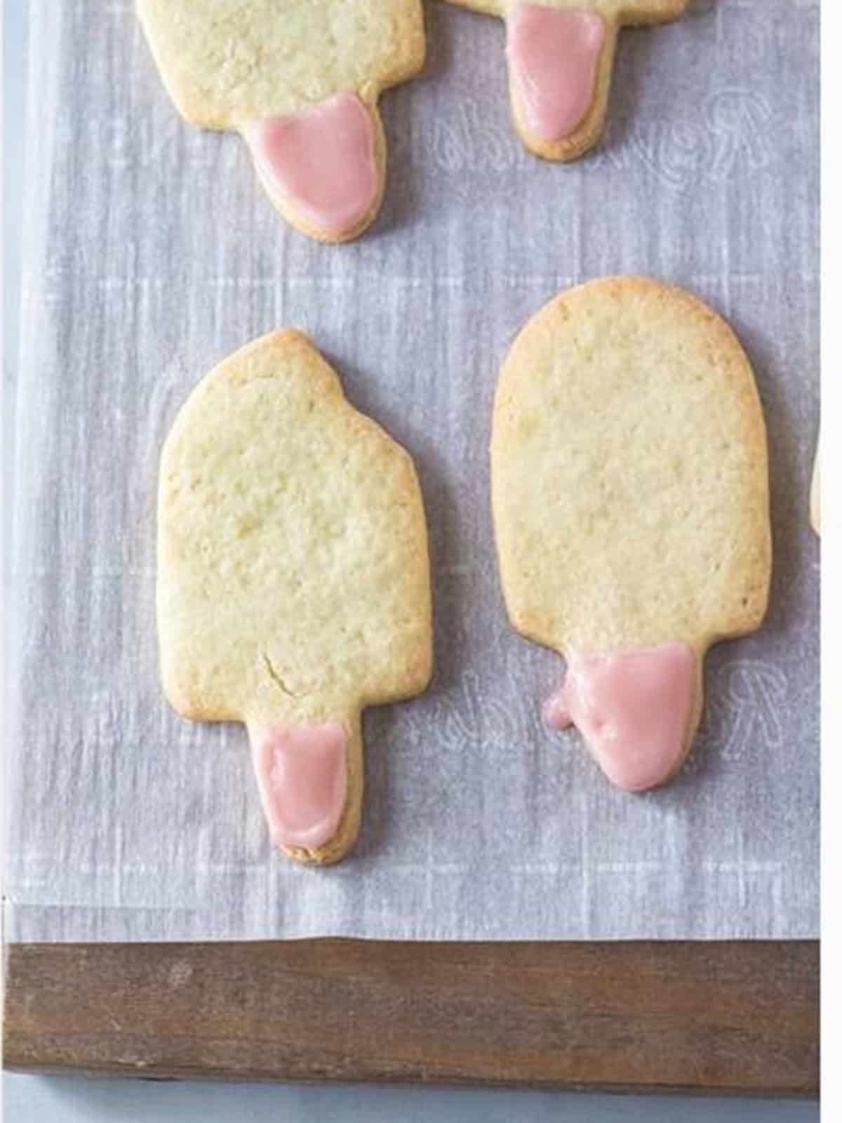 Baked popsicle shaped sugar cookies cooling on parchment paper.