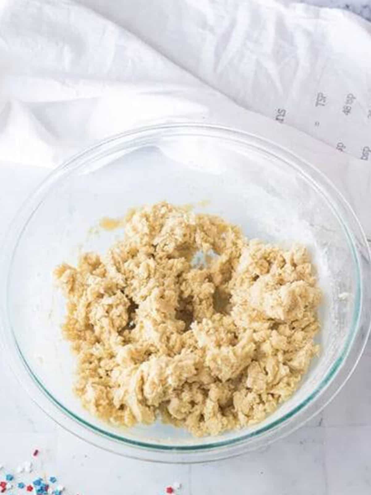 Cut out sugar cookie dough mixed in a glass bowl.