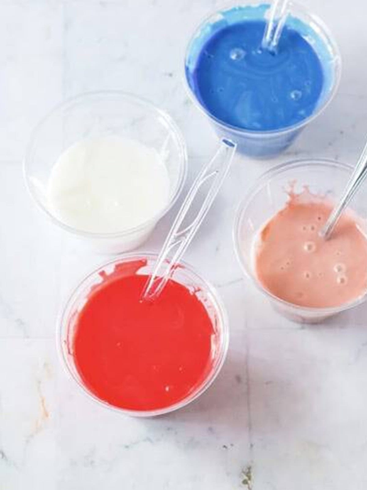 Bowls of red, white, and blue royal icing for decorating sugar cookies.