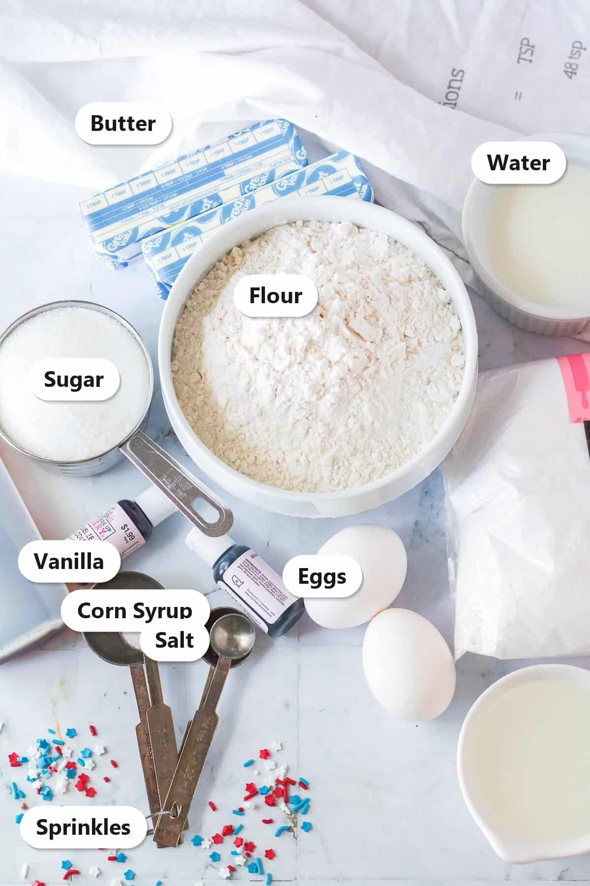 Labeled cut out sugar cookie ingredients including butter, flour, sugar, eggs, corn syrup, and sprinkles.