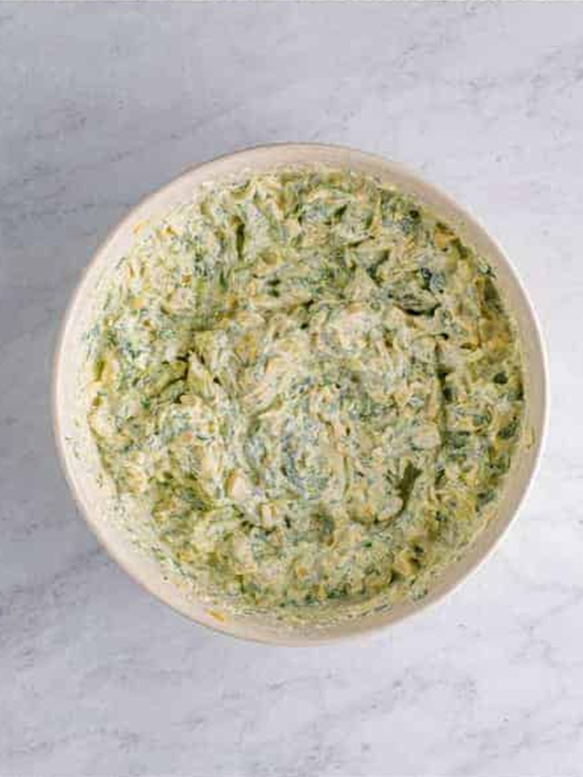 Spinach artichoke dip ingredients mixed together in a bowl.