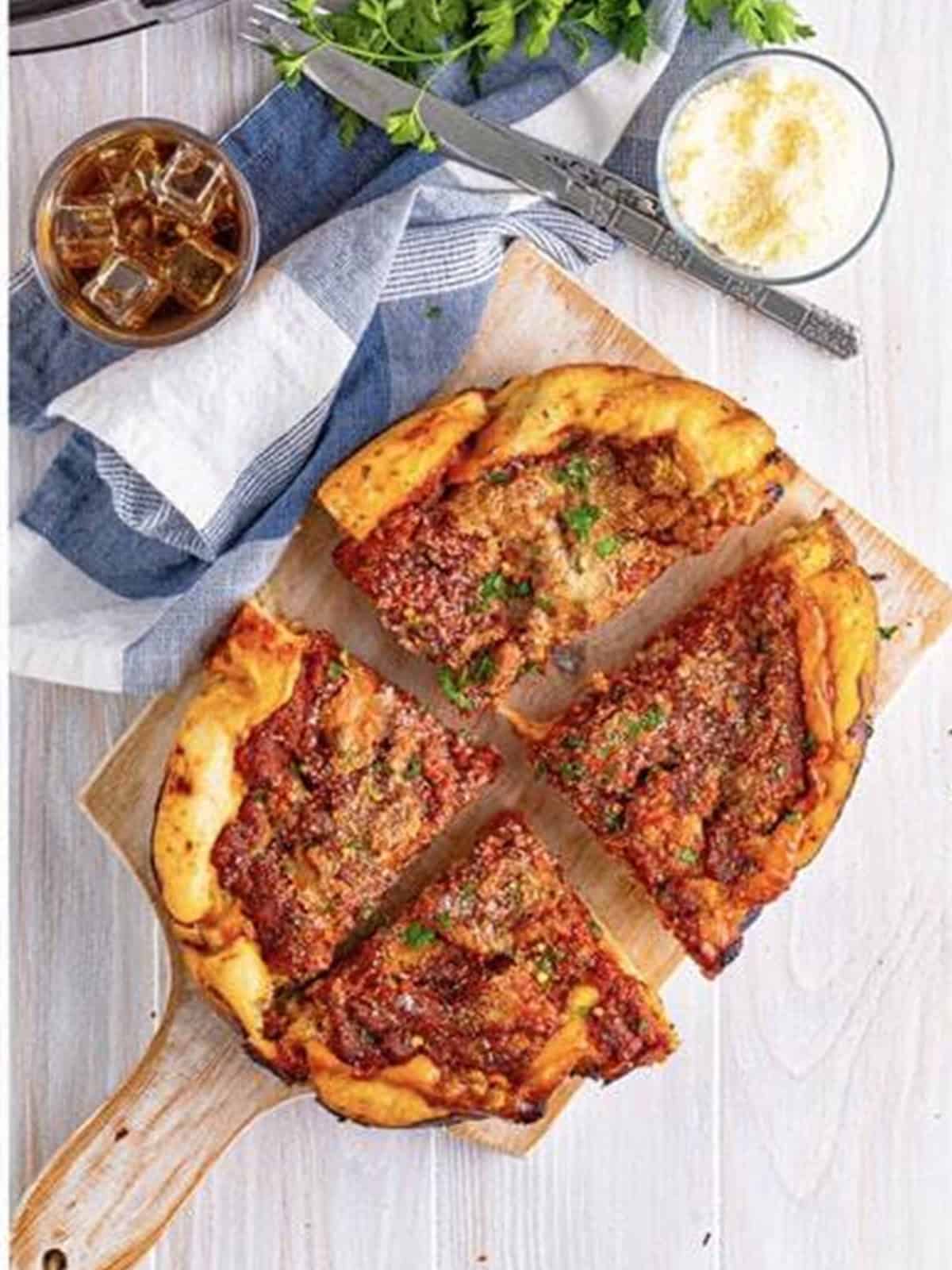 Sliced deep dish pizza served on a plate with fresh parsley.