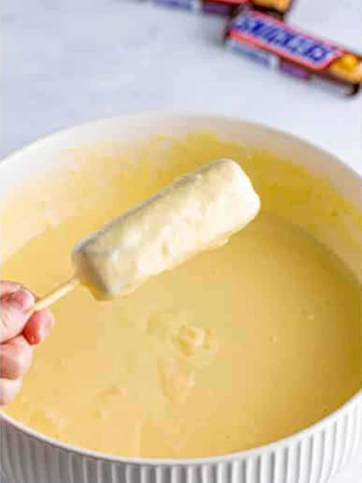 A skewered frozen Snickers bar dipped into the thick batter.