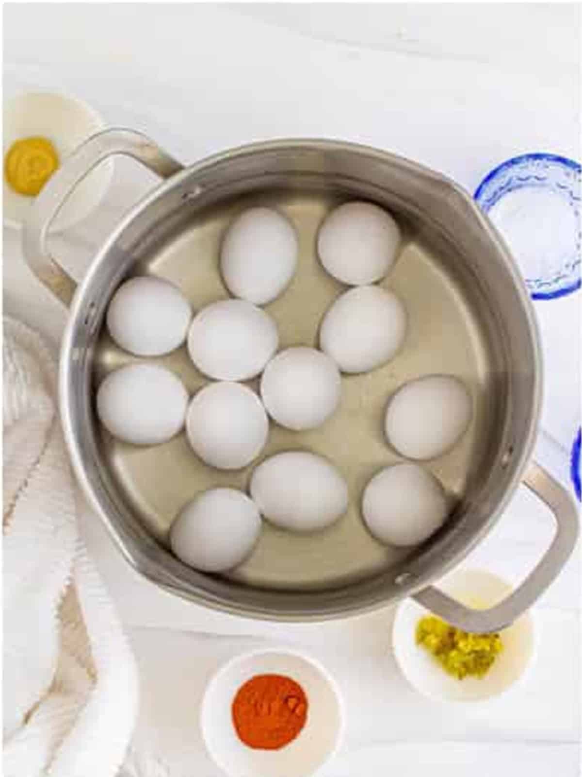 Eggs boiling in a pot of water to hard cook them for deviled eggs.