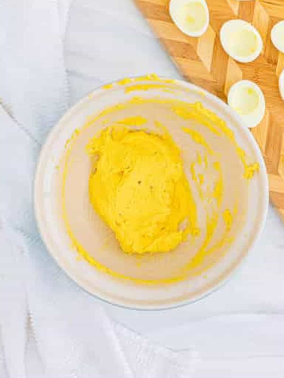 Deviled egg filling being piped into the hard boiled egg white halves.