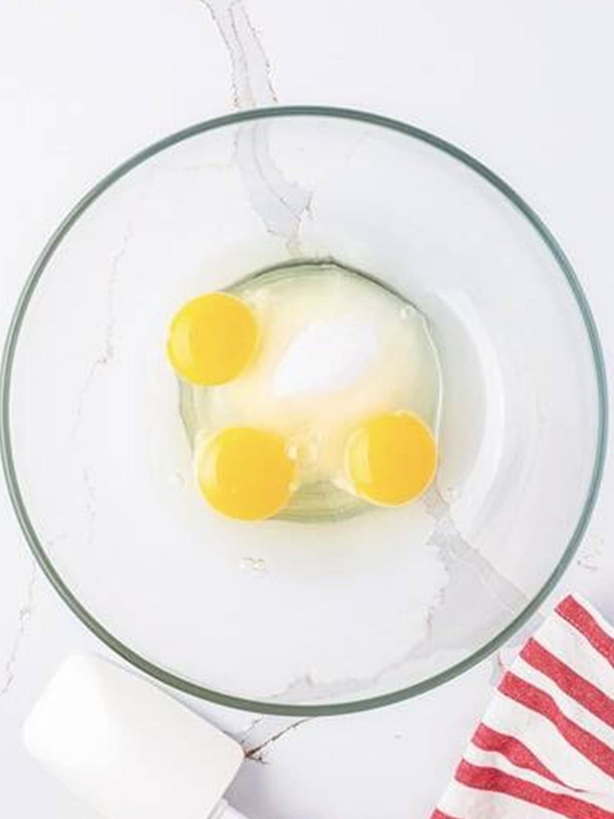 Eggs and sugar being beaten together in a glass bowl for deep fried Twinkie batter.