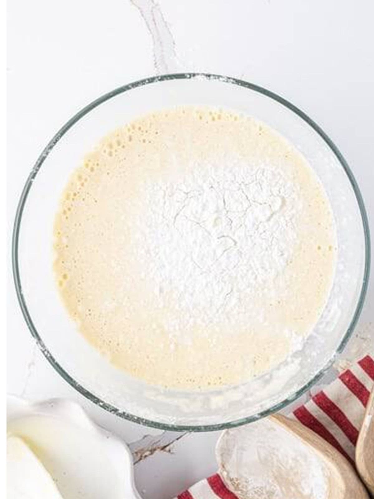 Flour being whisked into the milk and egg mixture to make a smooth frying batter.