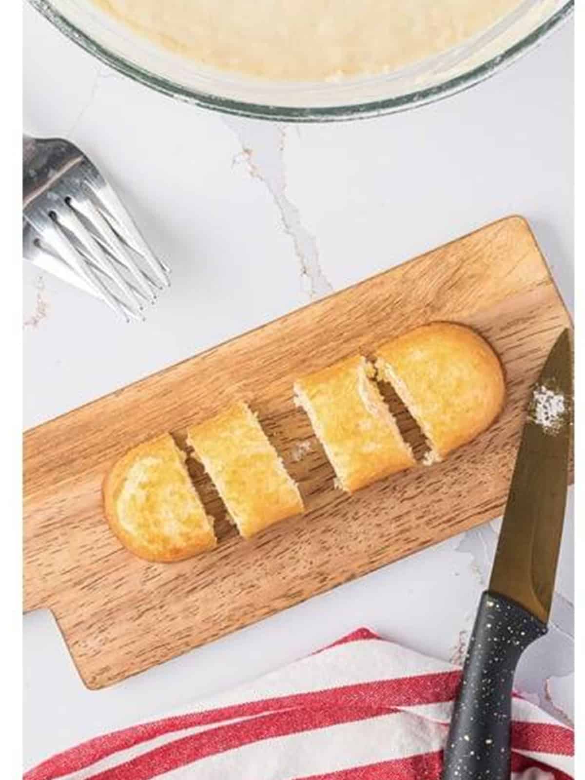 Frozen Twinkies cut into bite-sized pieces on a wood cutting board.