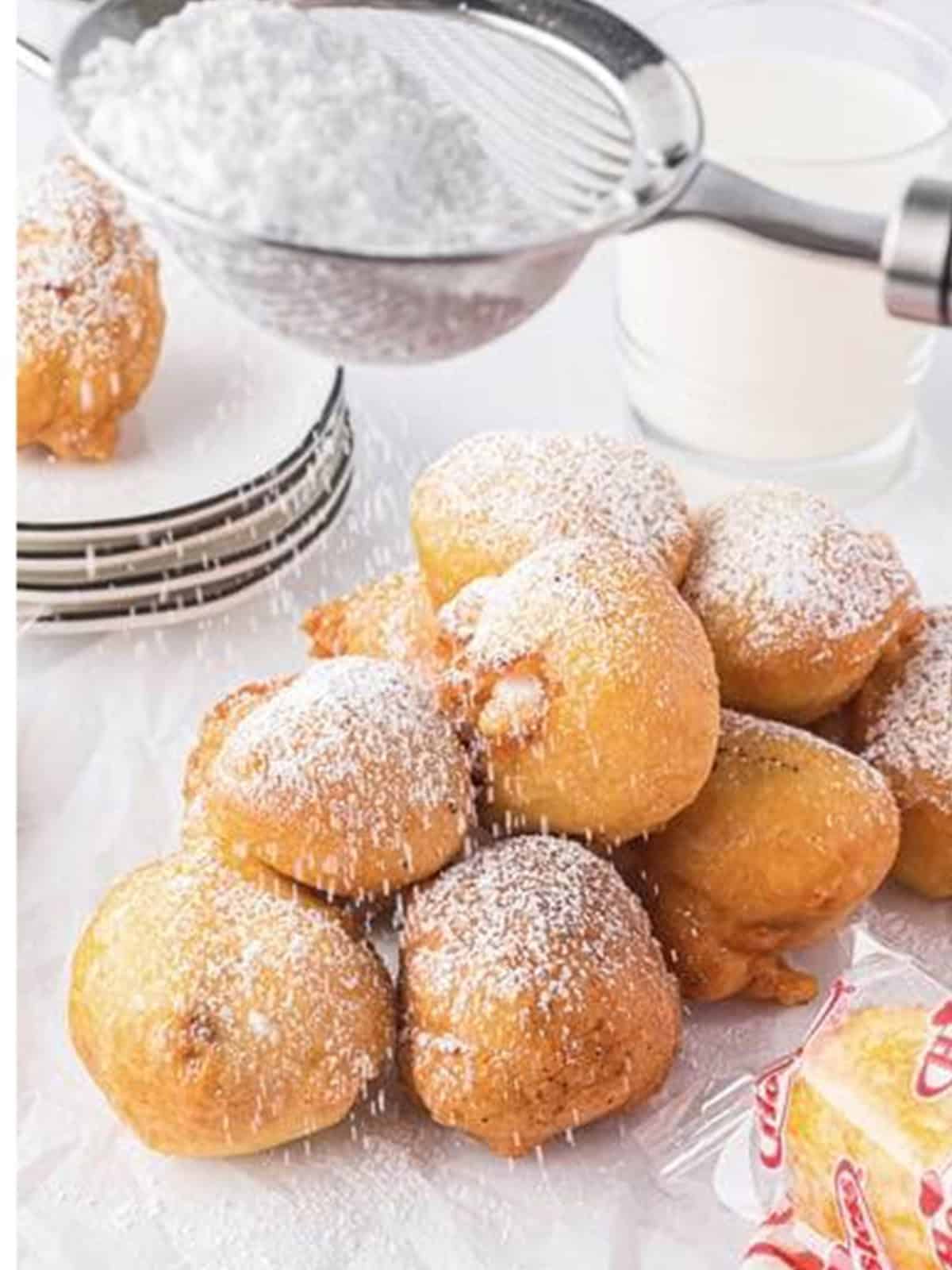 Deep fried Twinkie bites being dusted with powdered sugar.