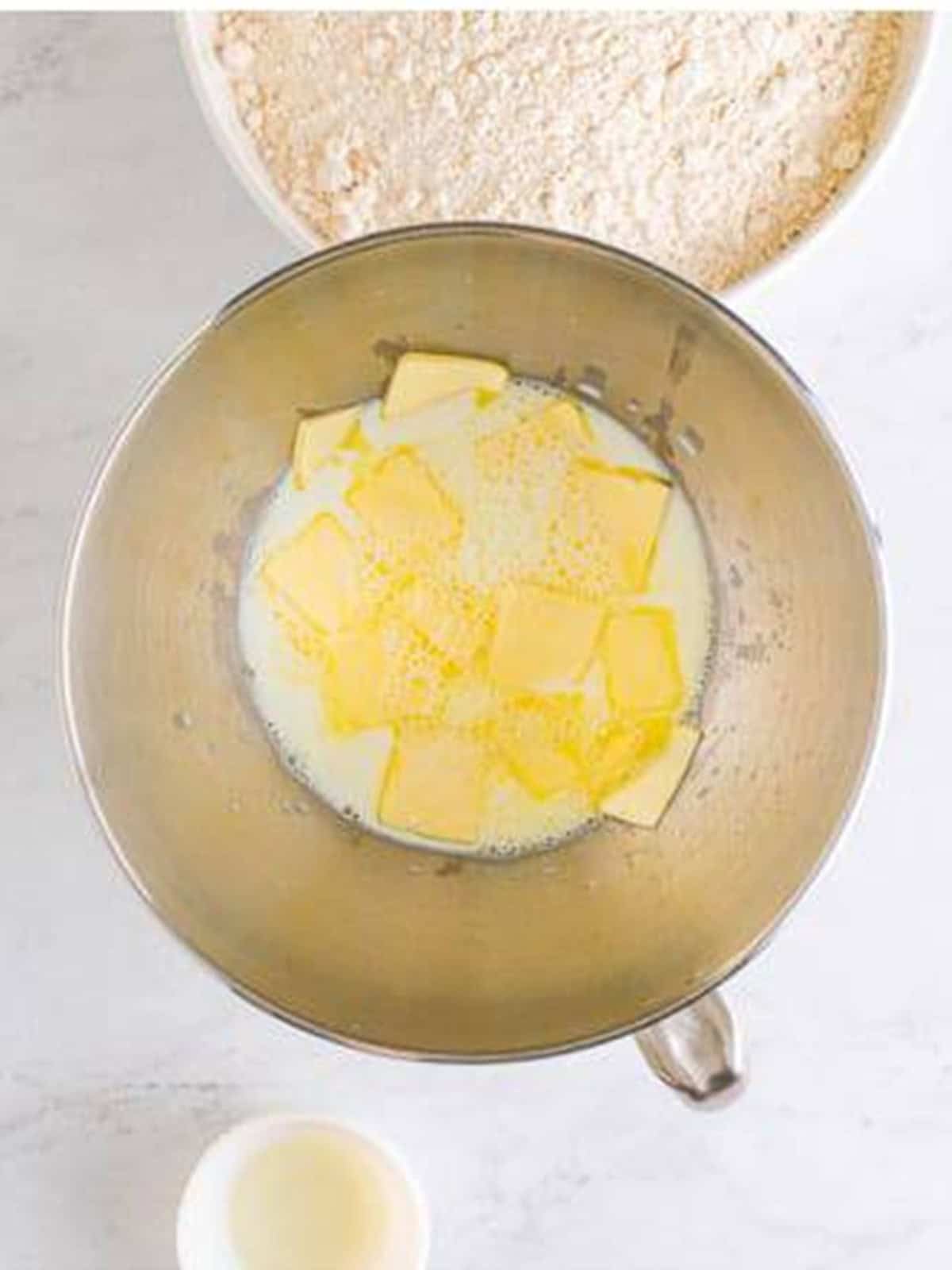Sliced butter, sugar, and salt in a stand mixer bowl for dinner rolls.