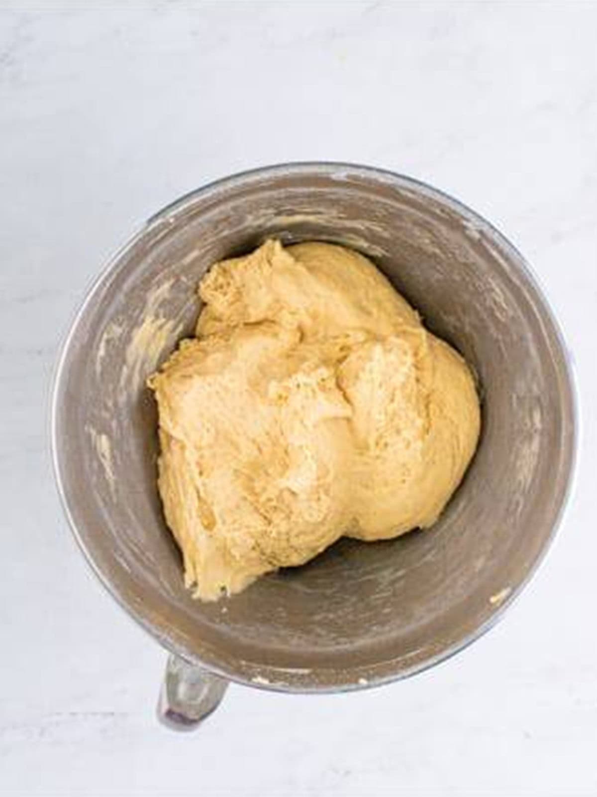 Smooth dinner roll dough kneaded in a stand mixer bowl.