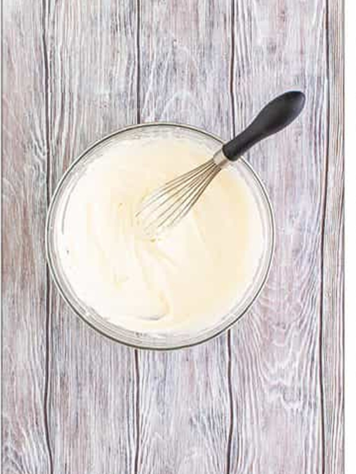Whipped cream beaten to stiff peaks in a glass bowl.
