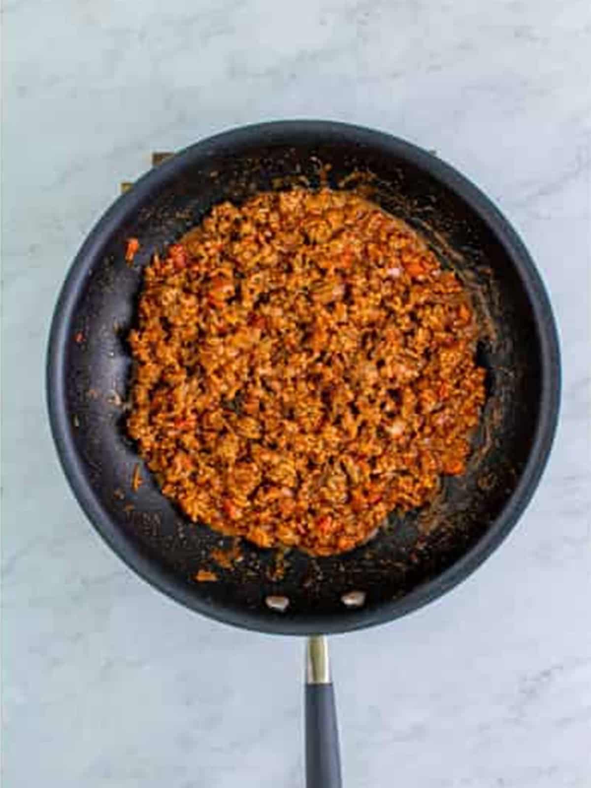 Simmering the seasoned beef with water and salsa for Doritos Taco Salad.