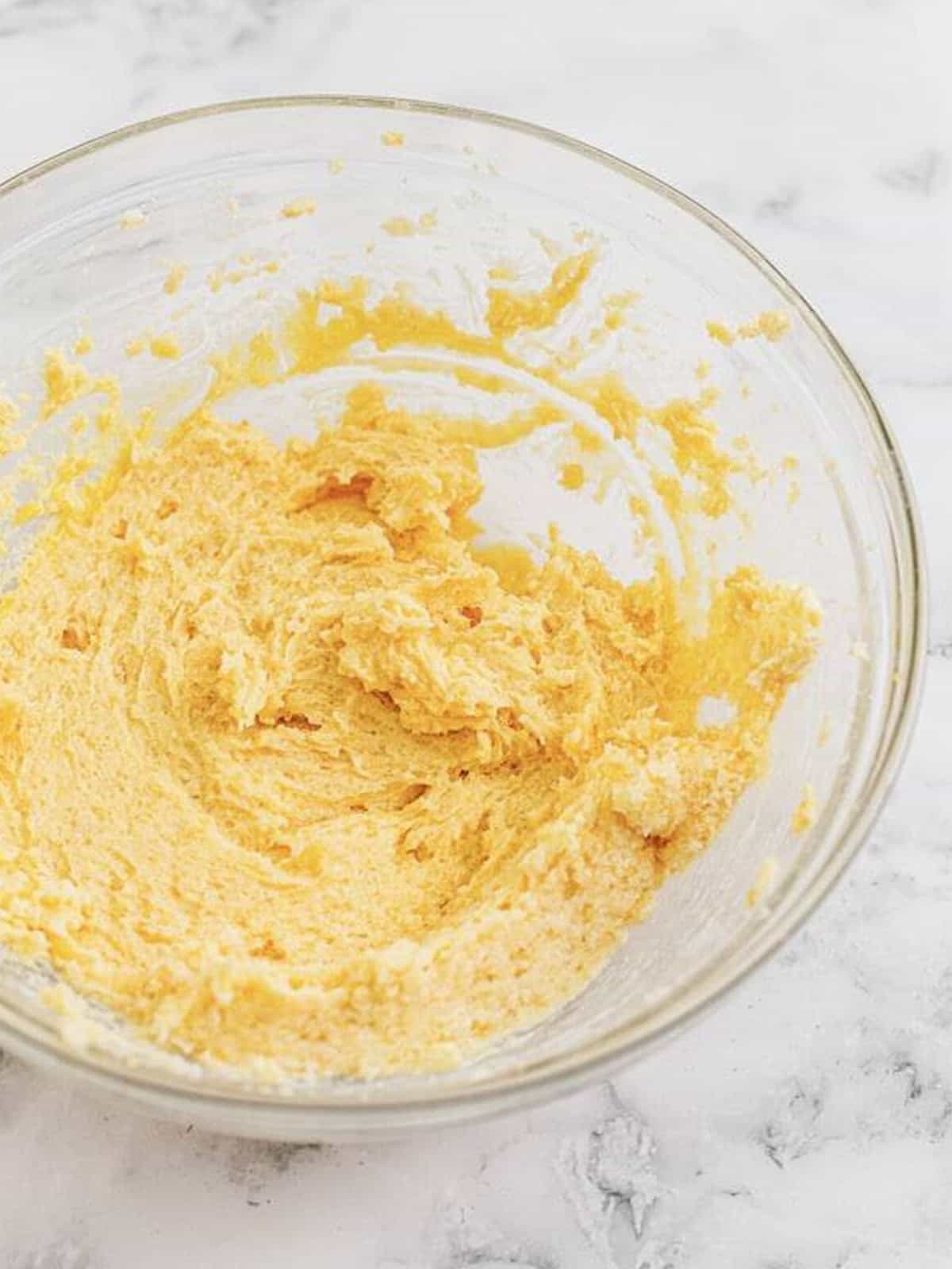 Creaming butter, granulated sugar, and brown sugar together in a glass bowl for double chocolate chip cookies.