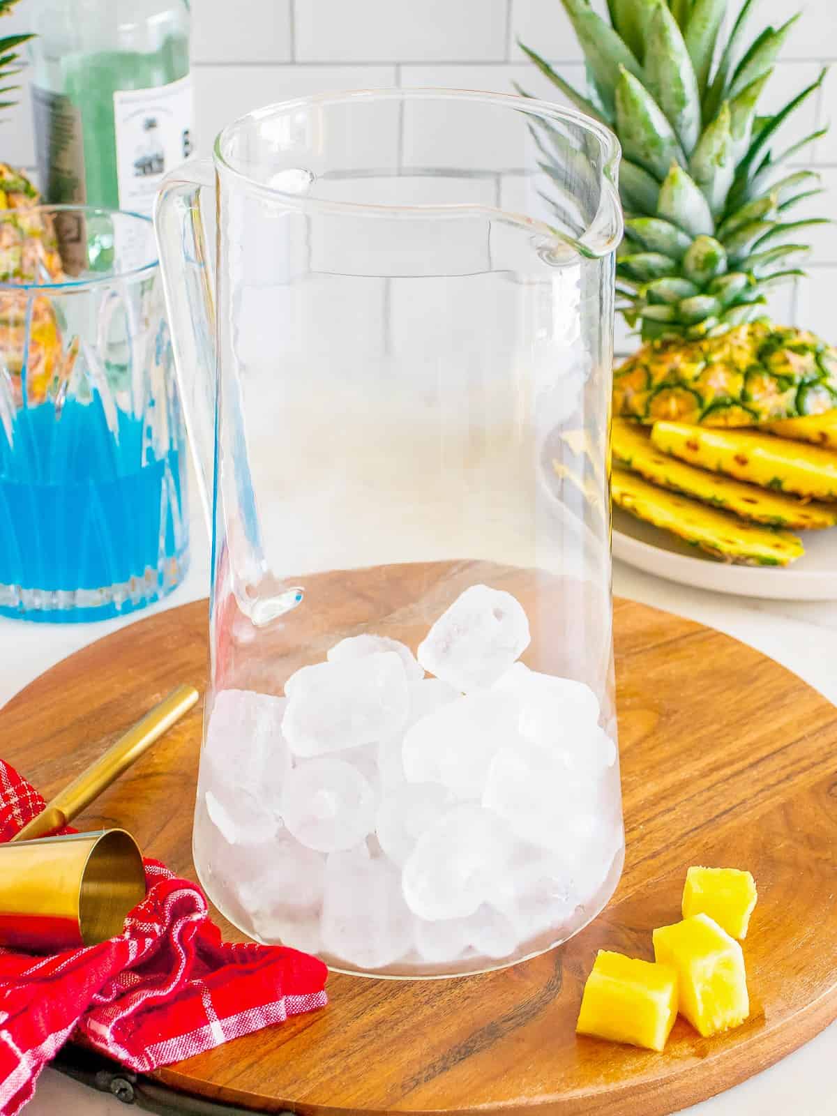 Ice cubes added to a glass pitcher for a Blue Hawaiian cocktail.