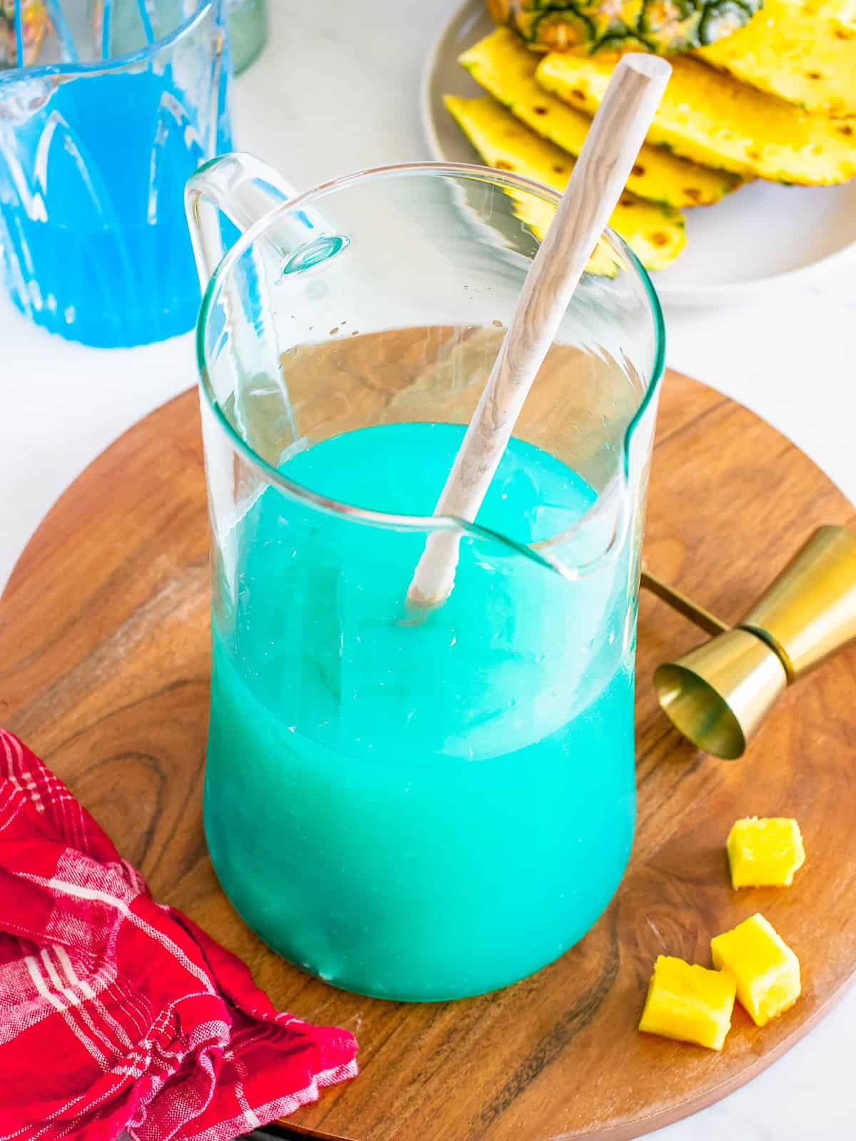 Blue Hawaiian cocktail stirred together in a pitcher with a stir stick.