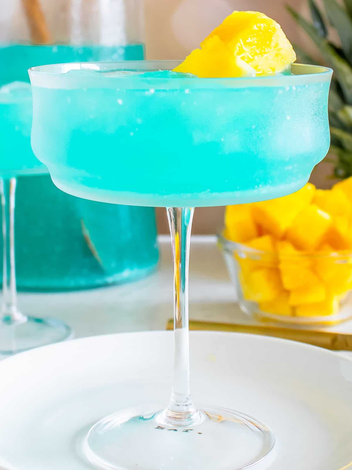 Blue Hawaiian cocktail poured into a coupe glass with pineapple garnish.