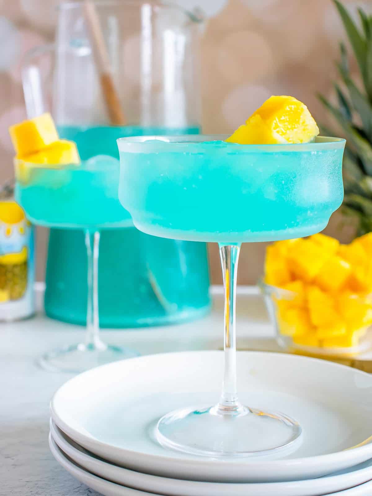 Two Blue Hawaiian cocktails garnished with pineapple and cherries.