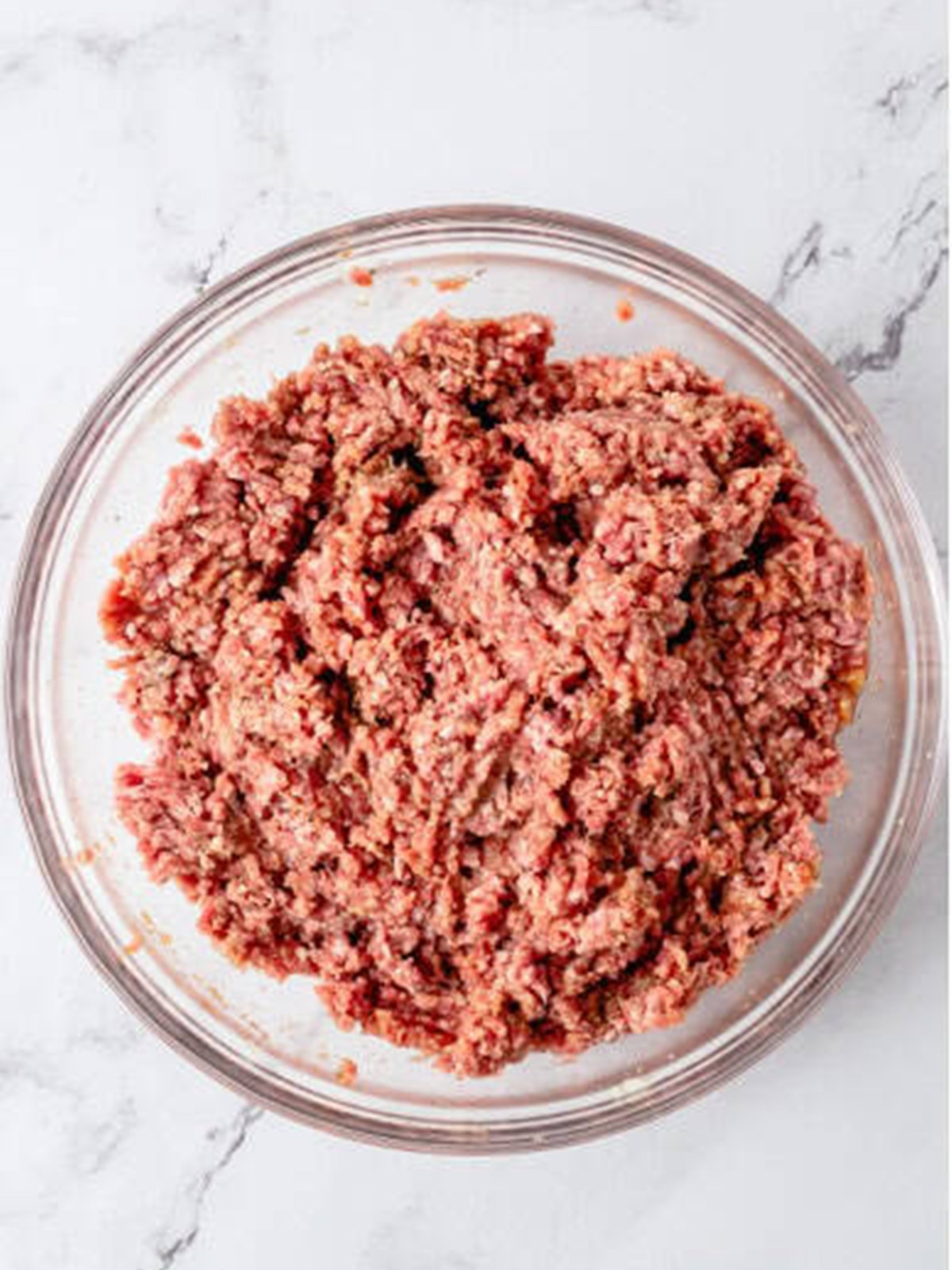 Ground beef meatloaf mixture mixed together in a glass bowl until just combined.