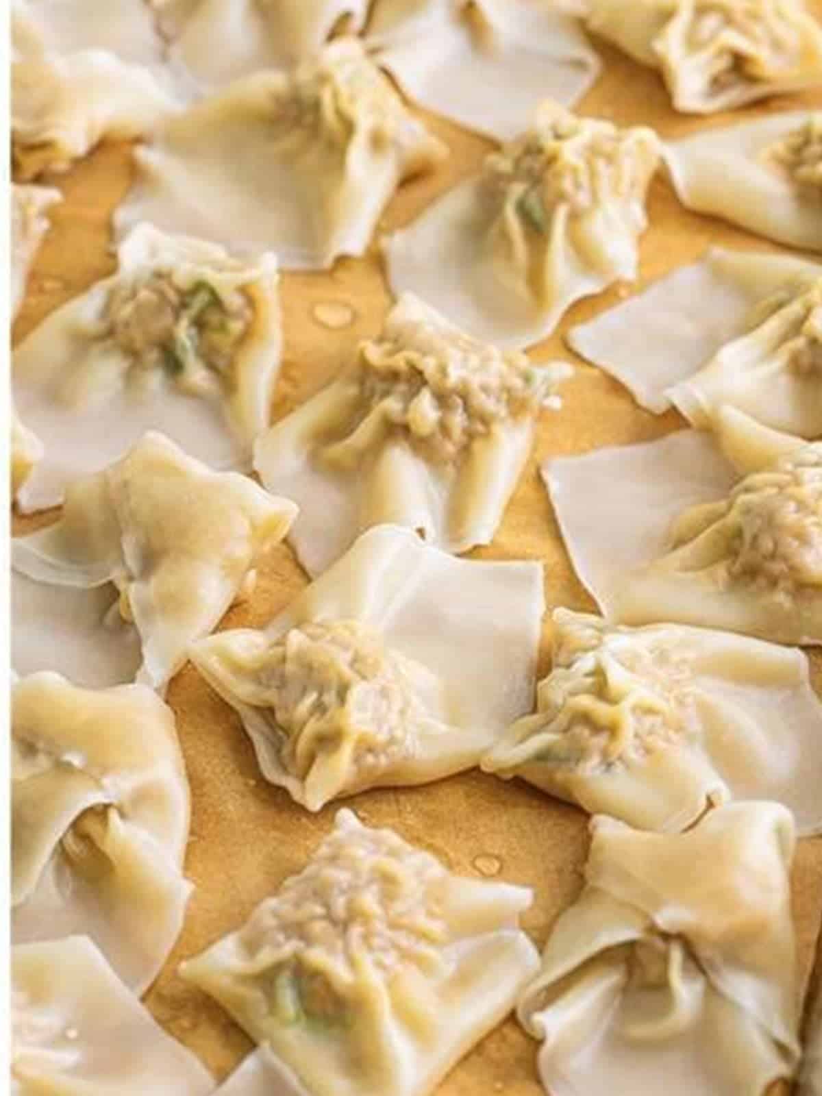 Cooked wontons resting on parchment paper.