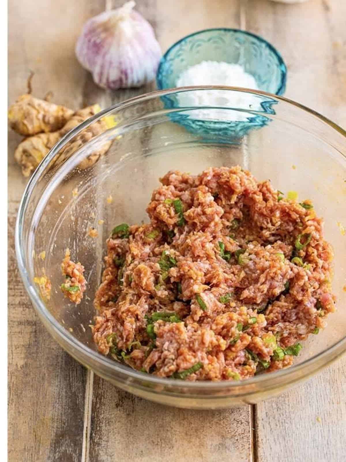 Seasoned ground pork wonton filling mixed in a glass bowl.