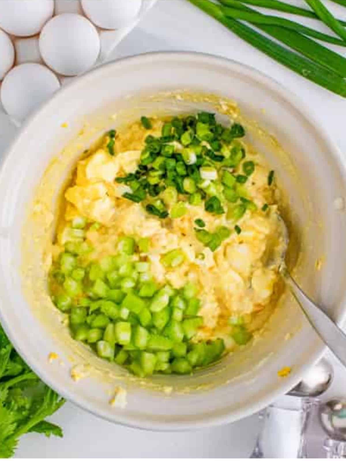 Diced celery and sliced scallions added to the egg salad for egg salad sandwich.