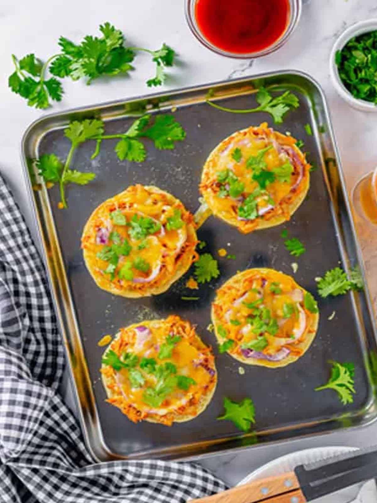 Baked BBQ chicken English muffin pizzas topped with melted cheese and fresh cilantro.