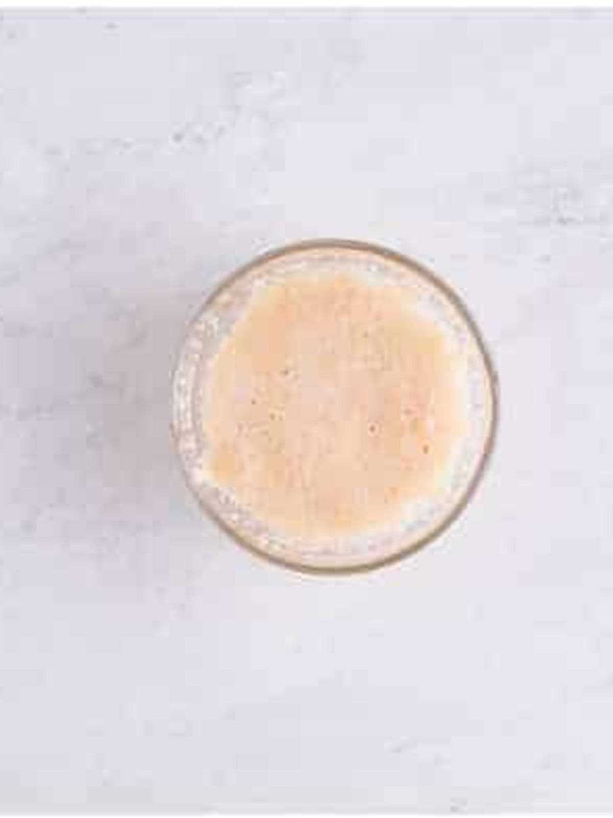 Active dry yeast blooming in warm water and sugar in a glass bowl.