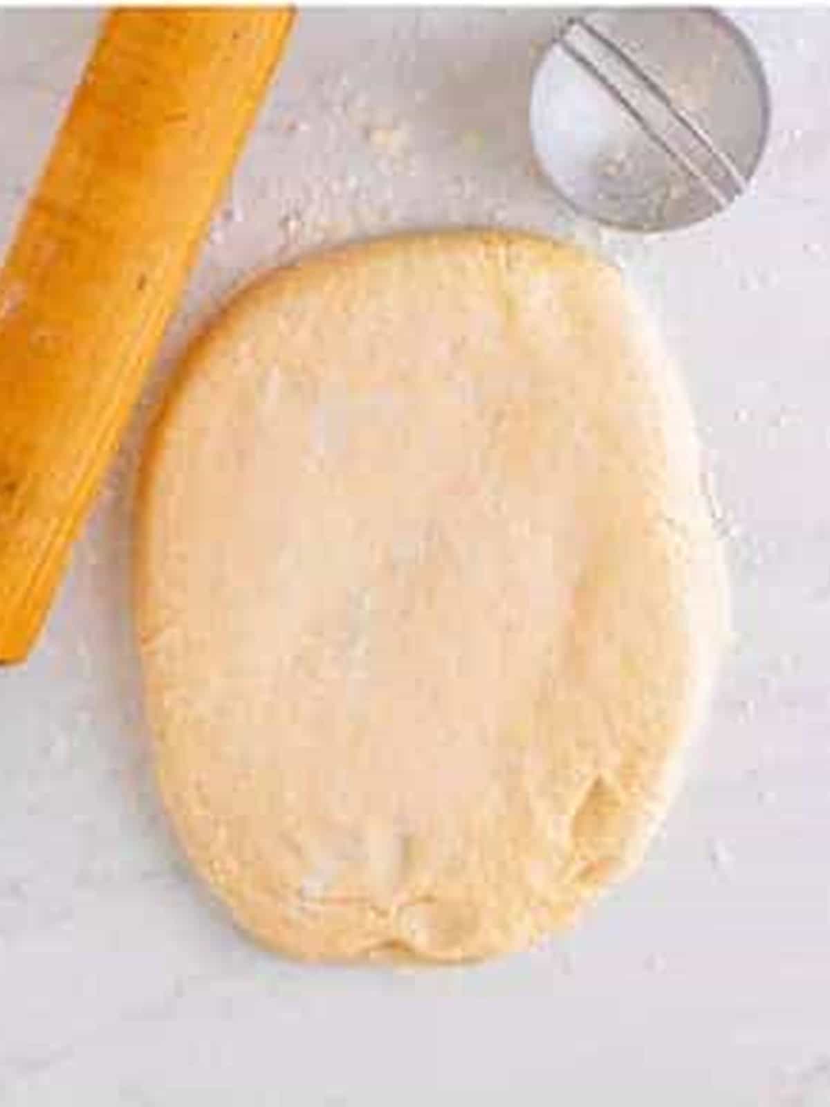 English muffin dough rolled out on a floured surface.