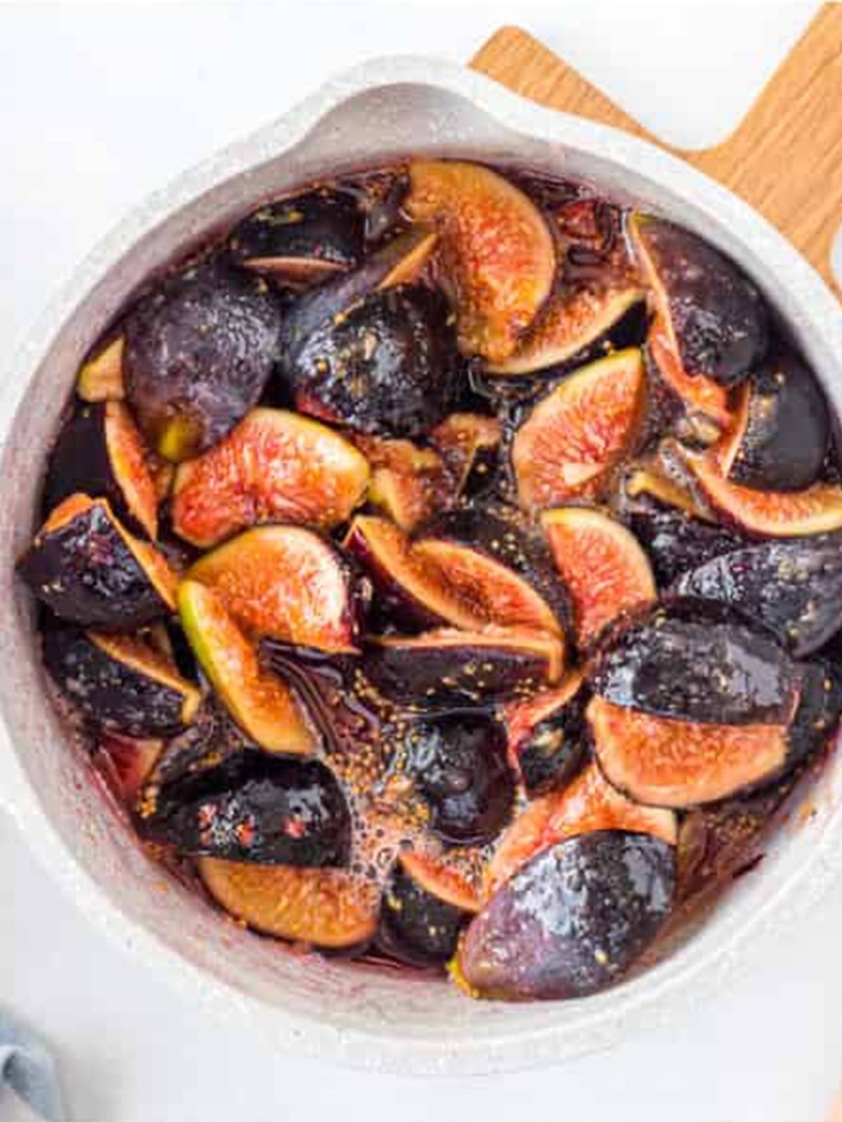 Fresh figs quartered on a cutting board for fig jam.