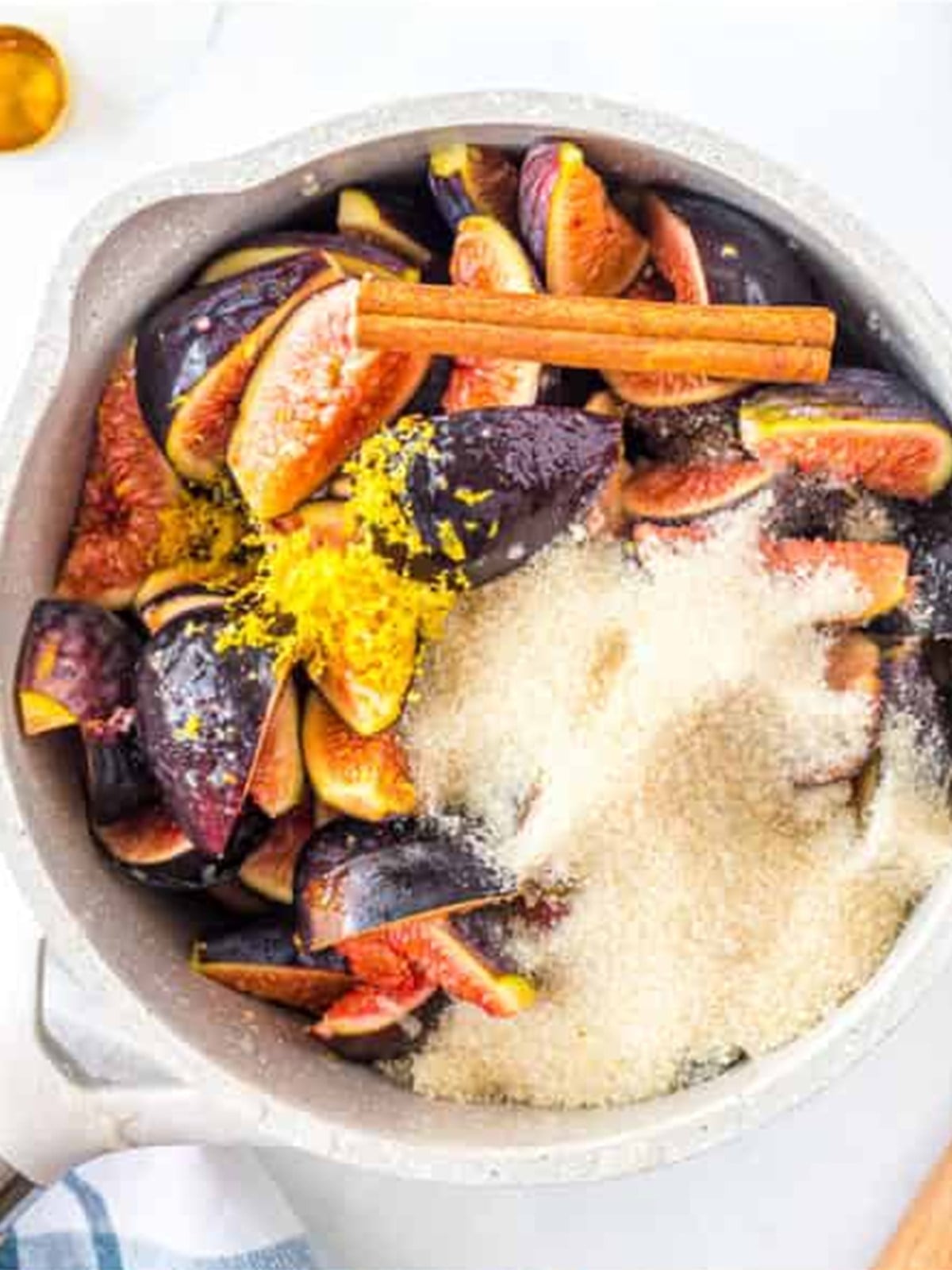 Figs, cane sugar, cinnamon stick, and lemon combined in a saucepan.