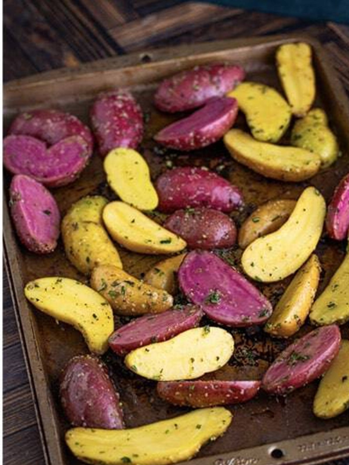 Seasoned fingerling potatoes spread cut side down on a baking sheet.