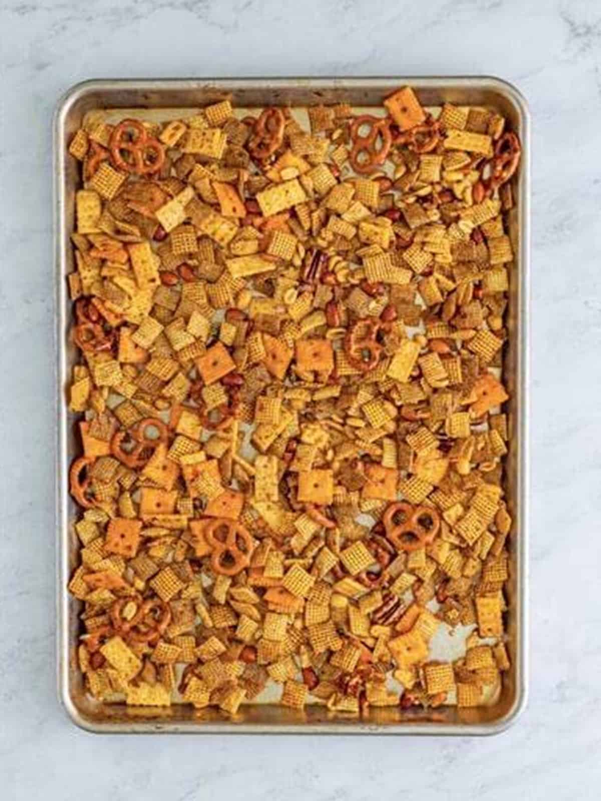 Firecracker chex mix spread in a single layer on a sheet tray ready to bake.