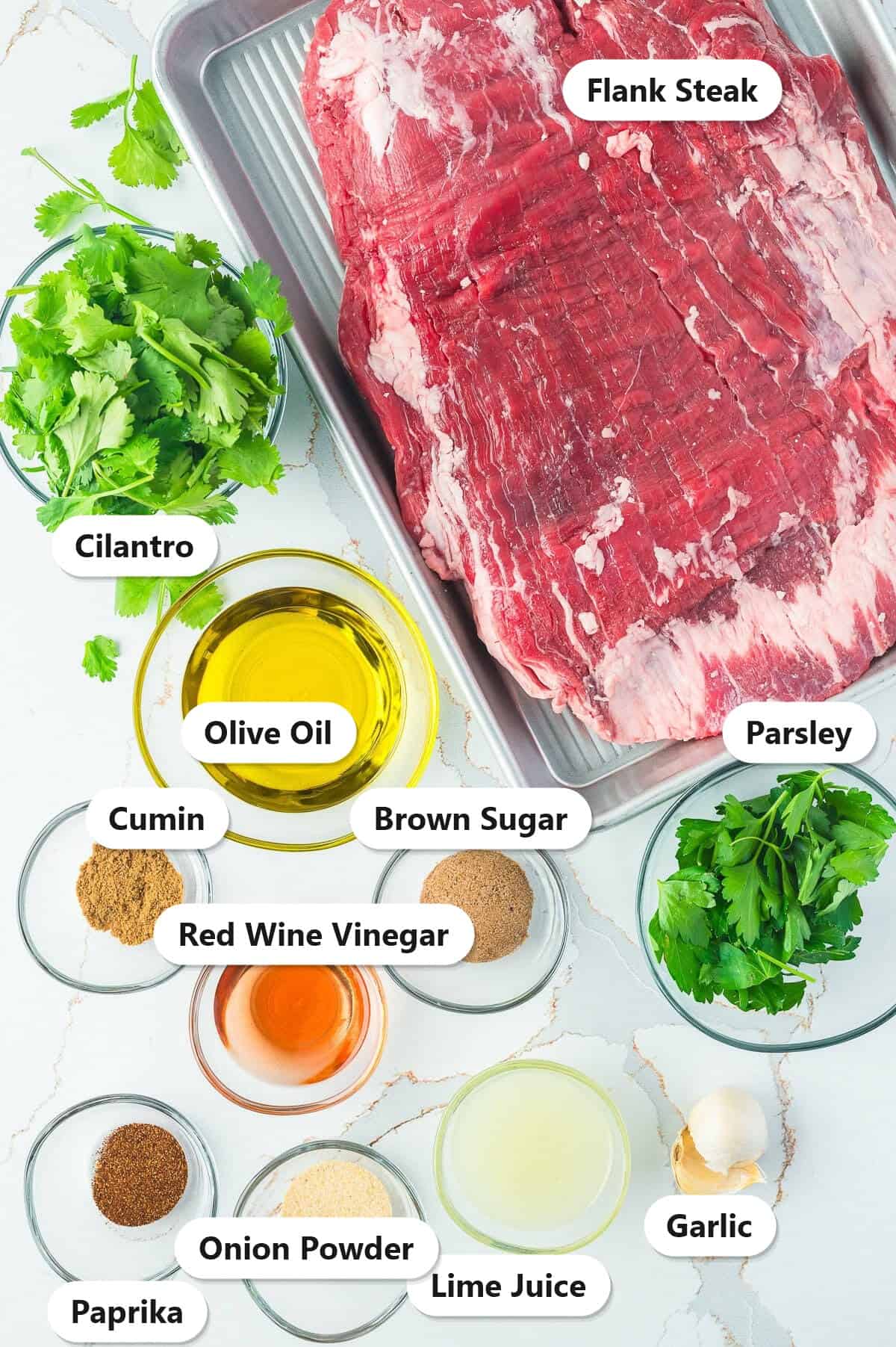 Labeled ingredients for flank steak chimichurri including flank steak, cilantro, parsley, olive oil, lime juice, red wine vinegar, brown sugar, garlic, cumin, paprika, and onion powder.