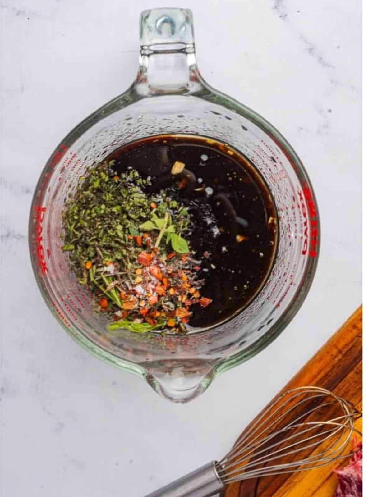 Whisking the balsamic flank steak marinade in a measuring cup.