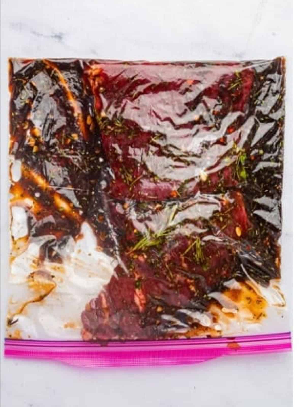 Flank steak marinating in the balsamic marinade in a bag.