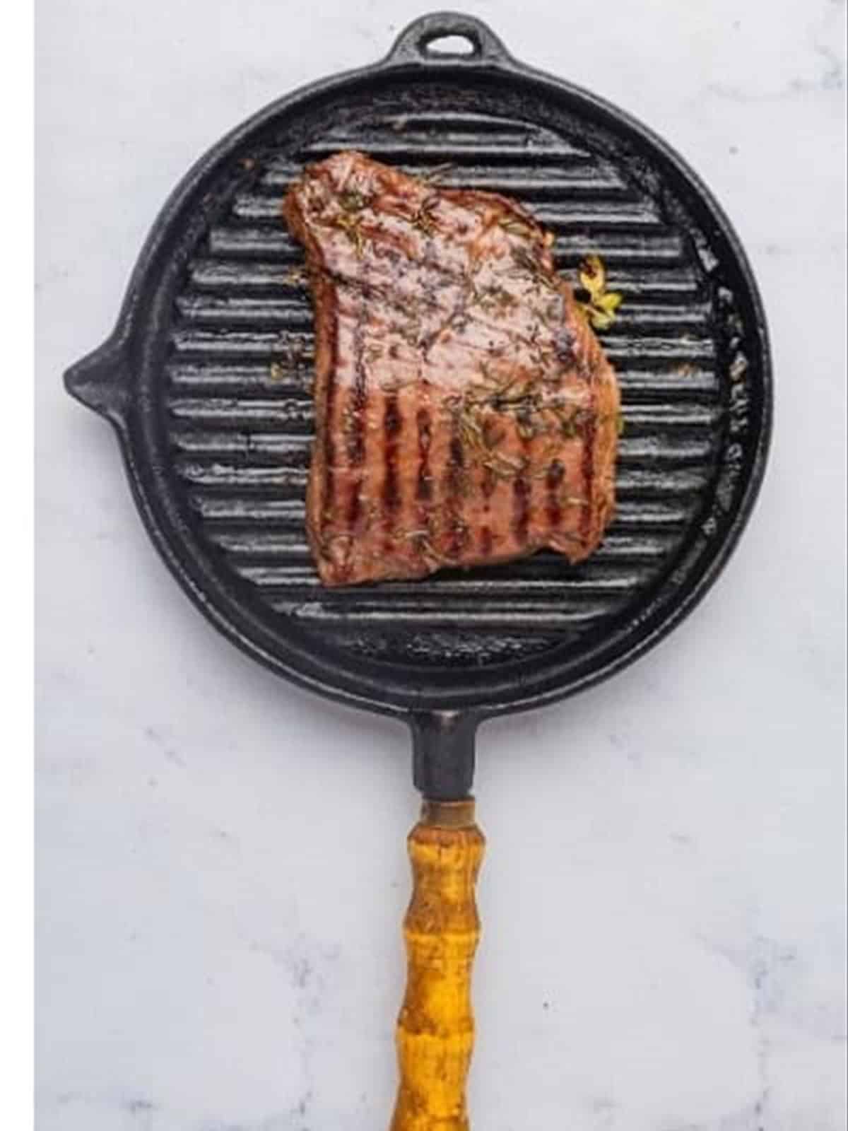 Grilling the marinated flank steak on a grill pan.