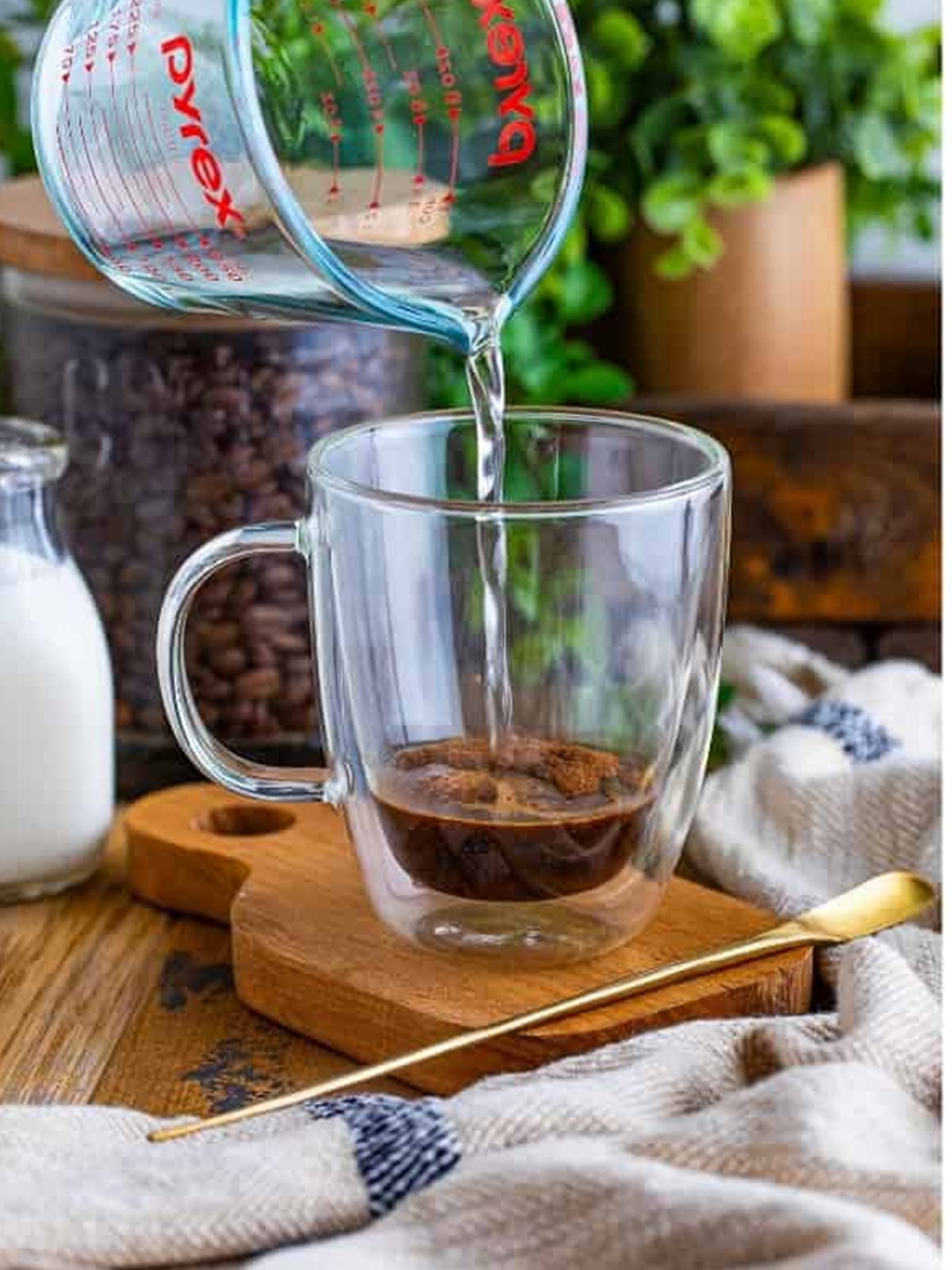 Pouring hot water over espresso powder in a glass mug
