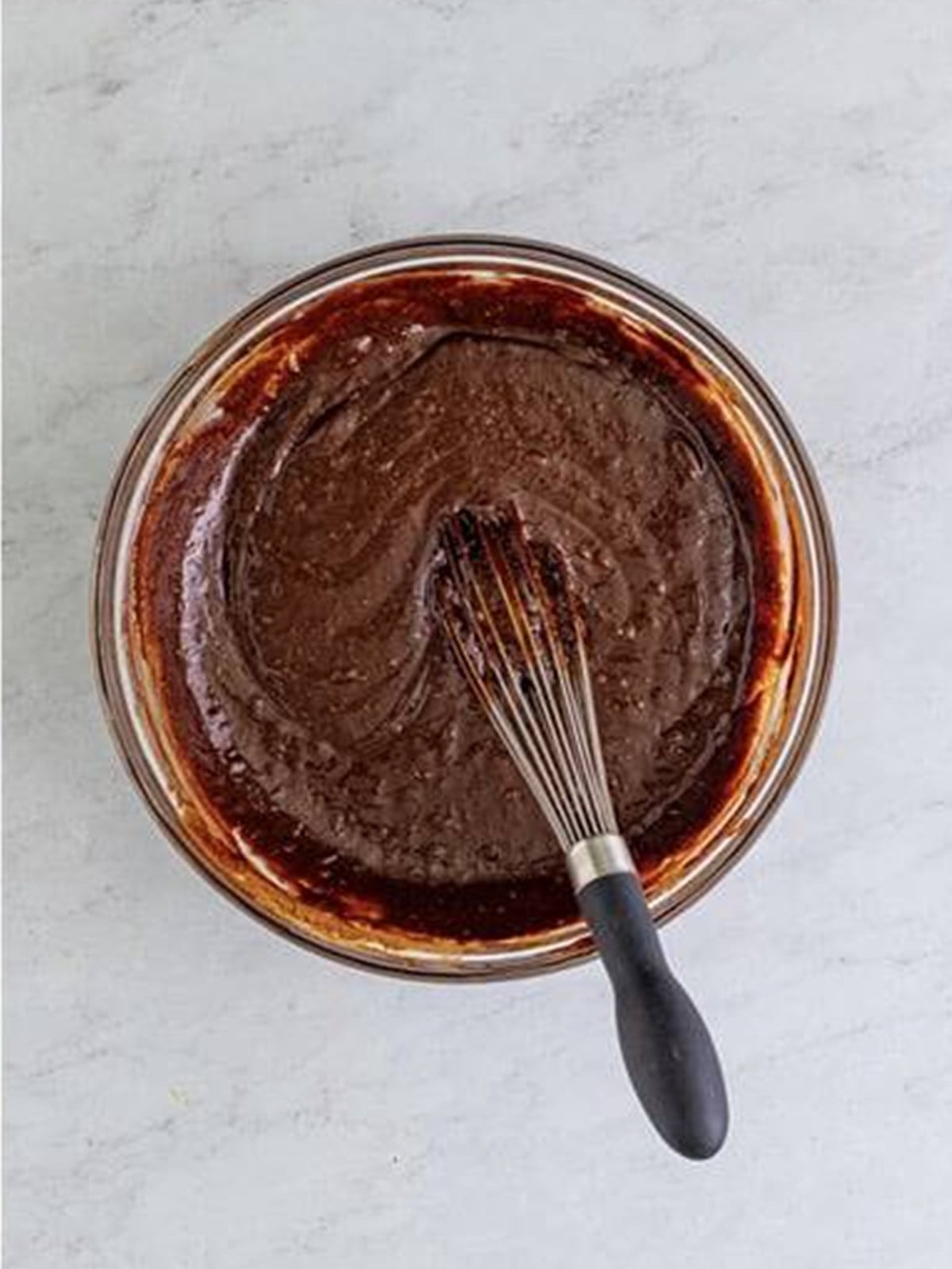 Smooth flourless chocolate cake batter whisked together in a bowl.