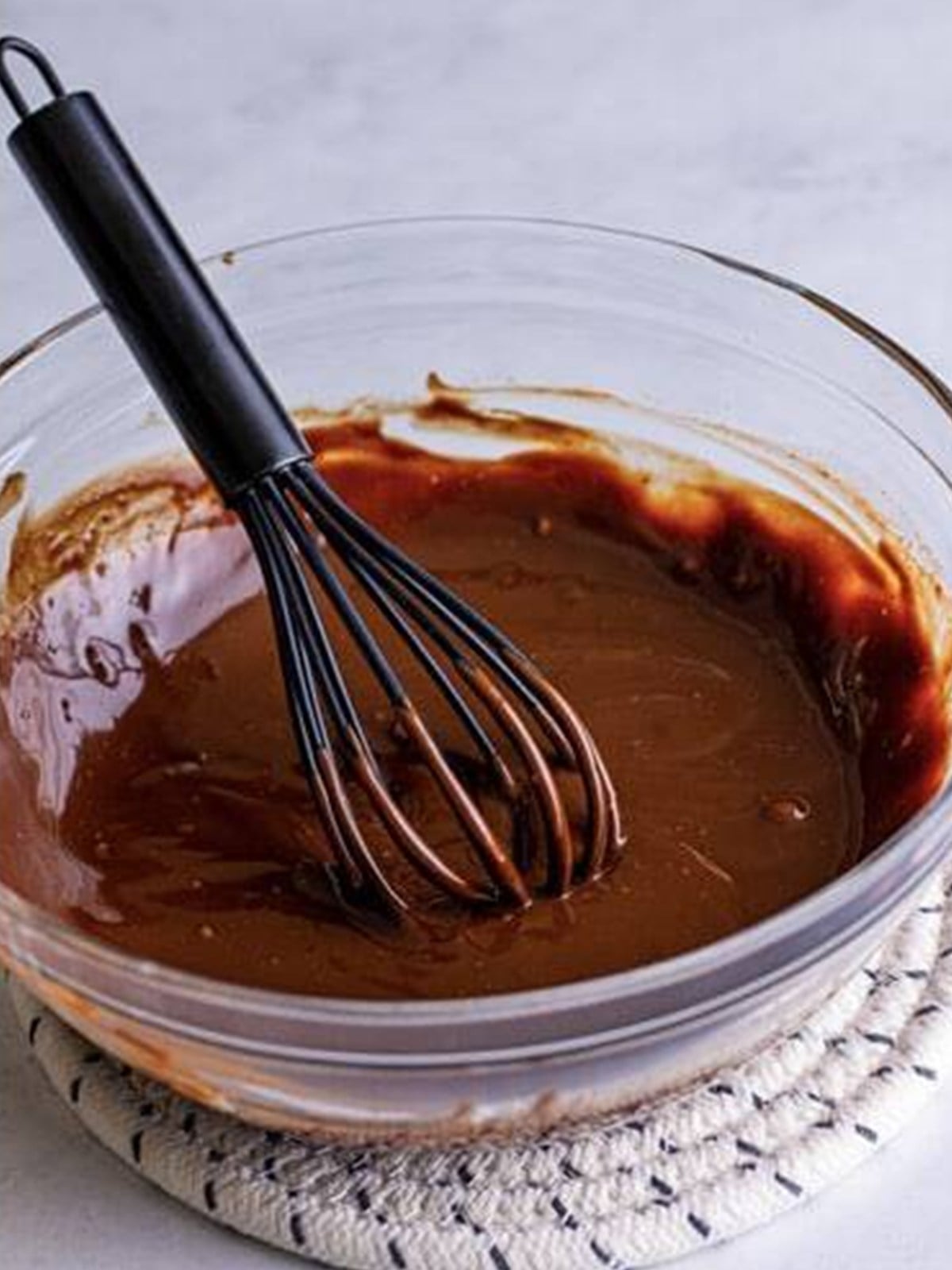 Chocolate ganache being whisked until smooth and glossy in a bowl.