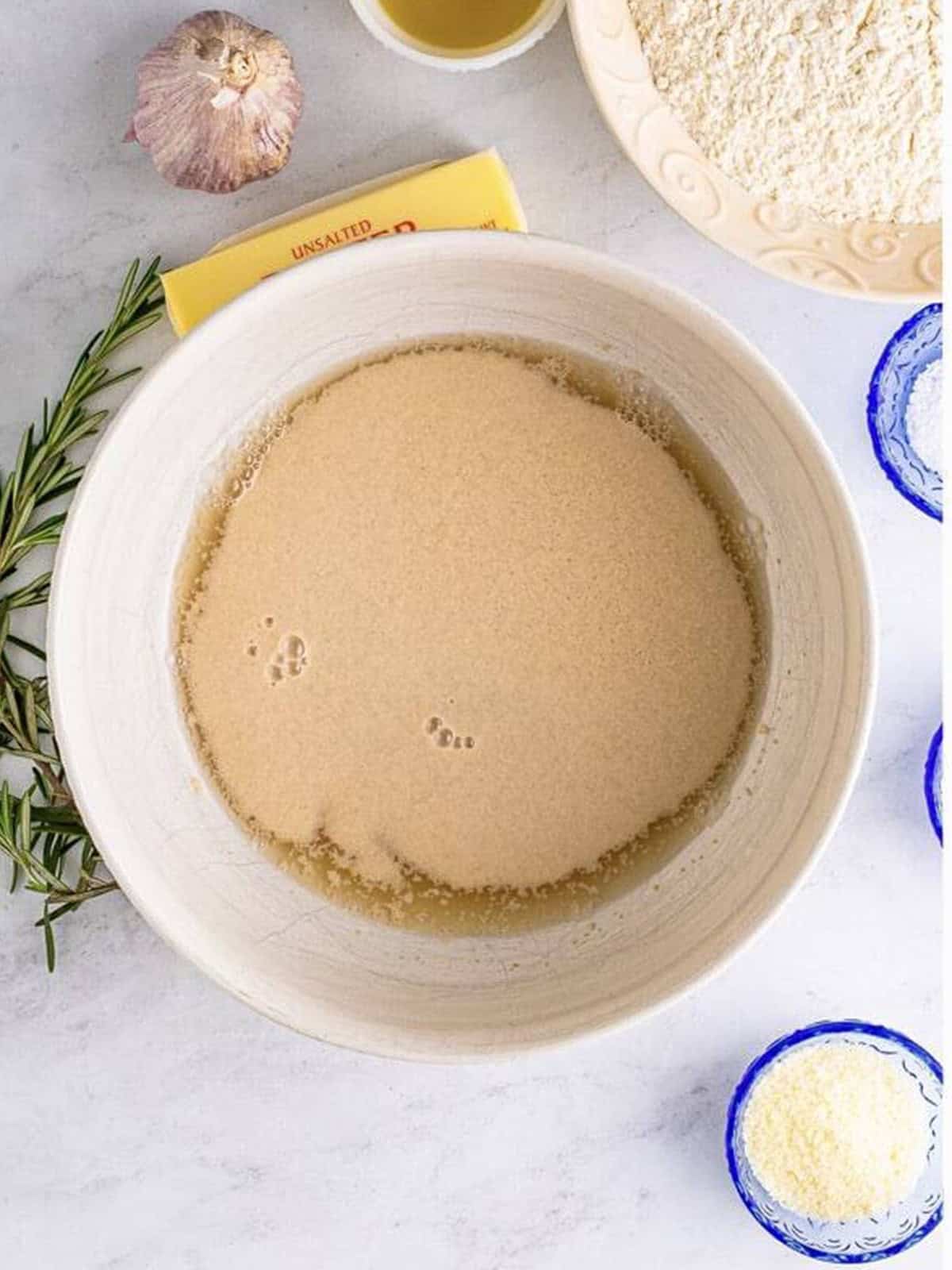 Yeast, warm water, and honey whisked together in a bowl to start the focaccia bread dough.