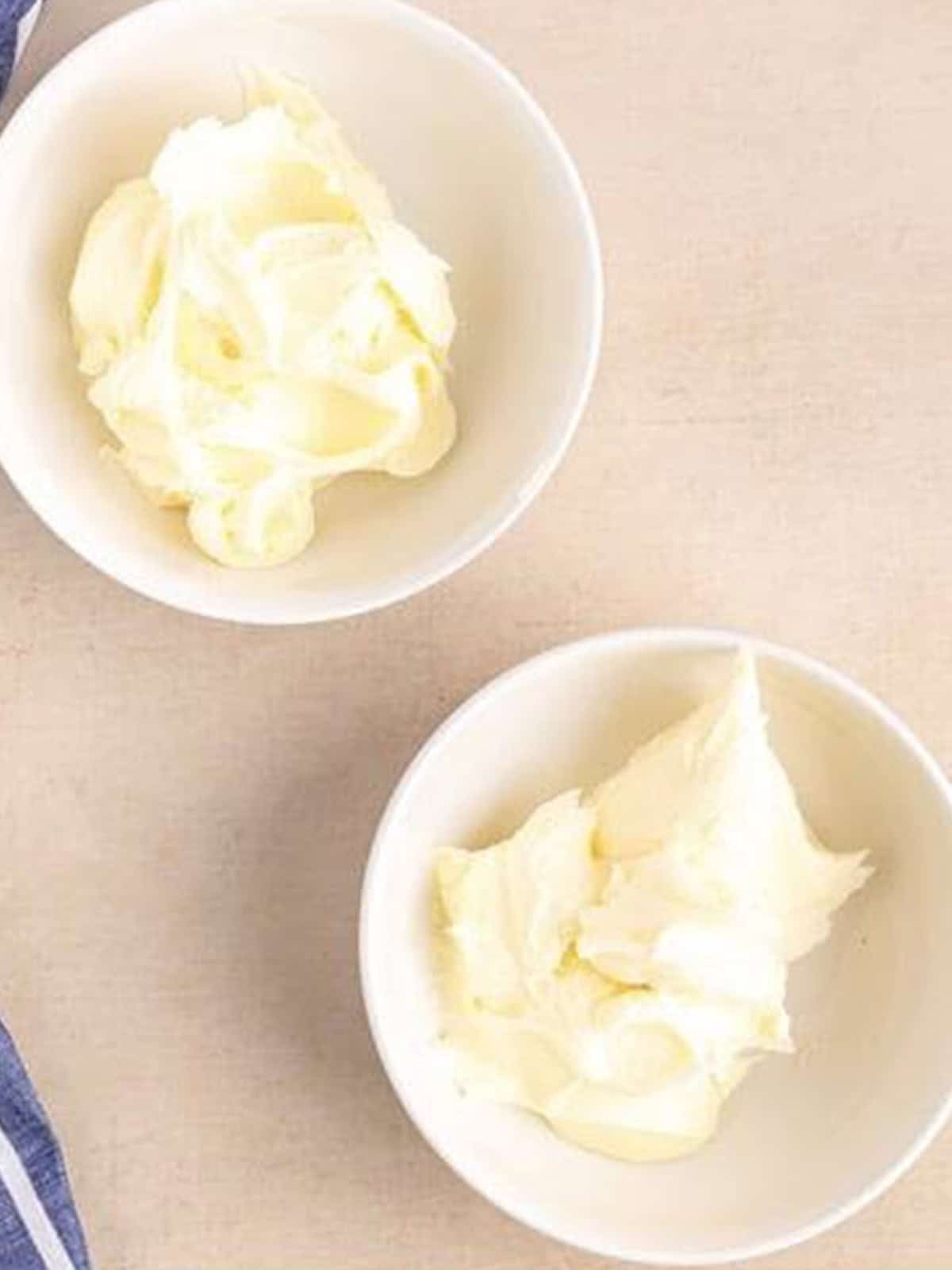 Vanilla frosting divided into white bowls for the ombre effect.