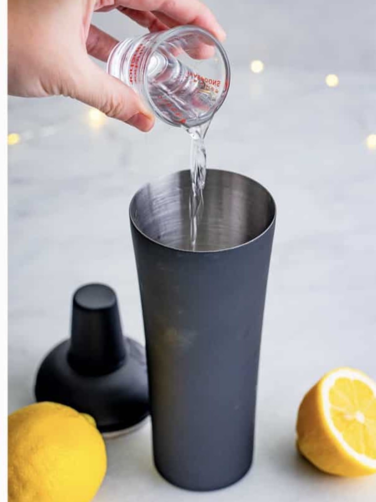 Pouring gin into the shaker for a French 75 cocktail.