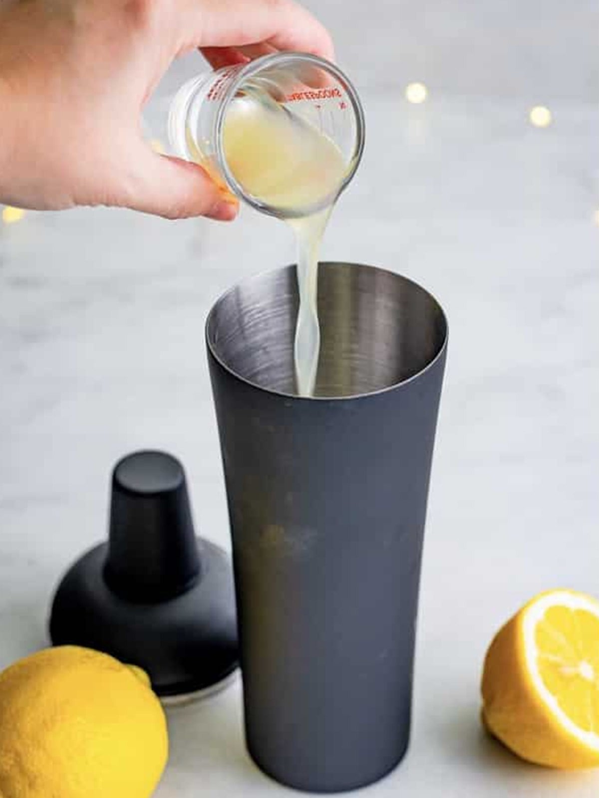 Adding fresh lemon juice to the French 75 cocktail shaker.