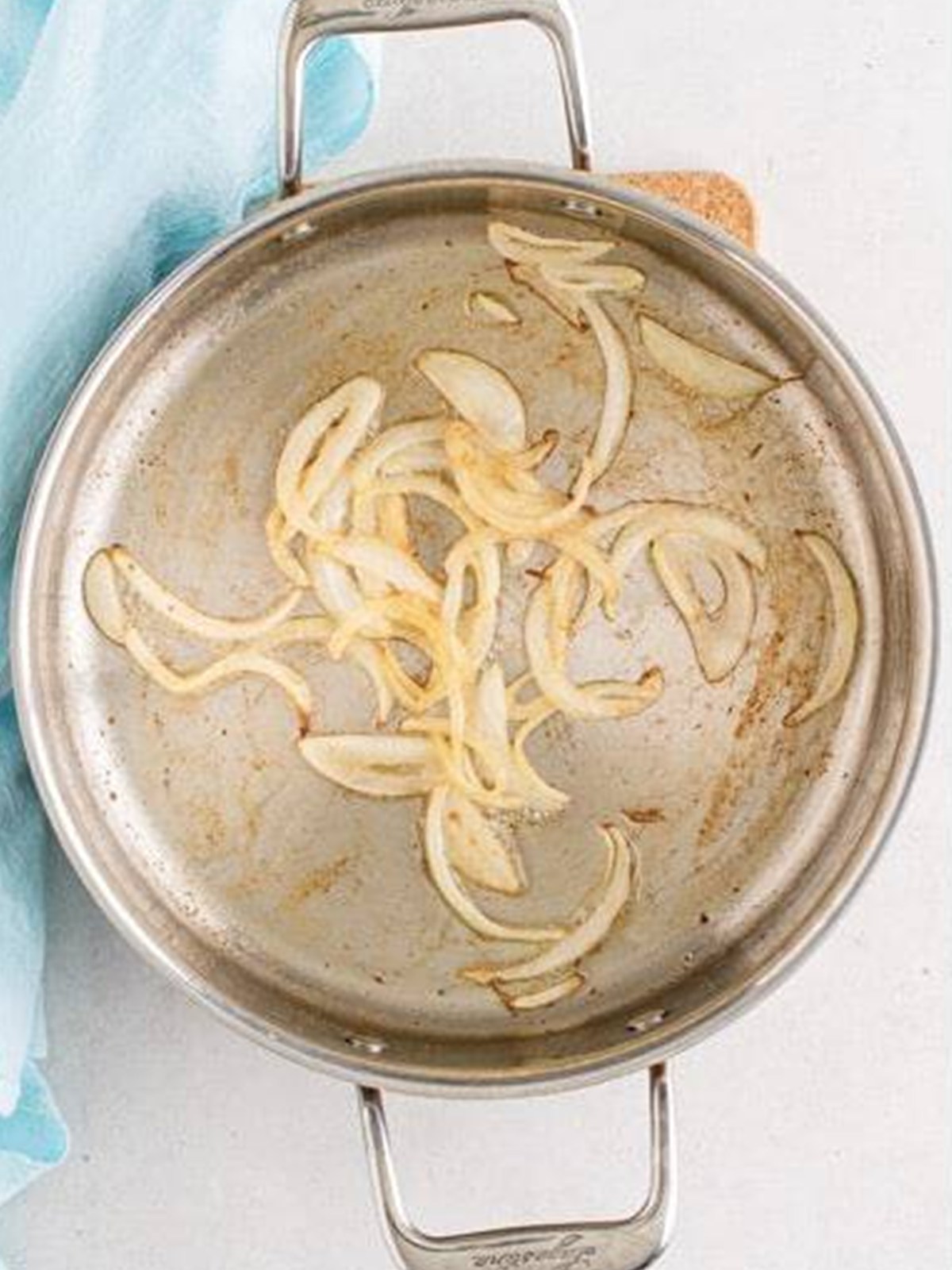 Sliced onions softening in butter in a skillet for French dip sandwiches.