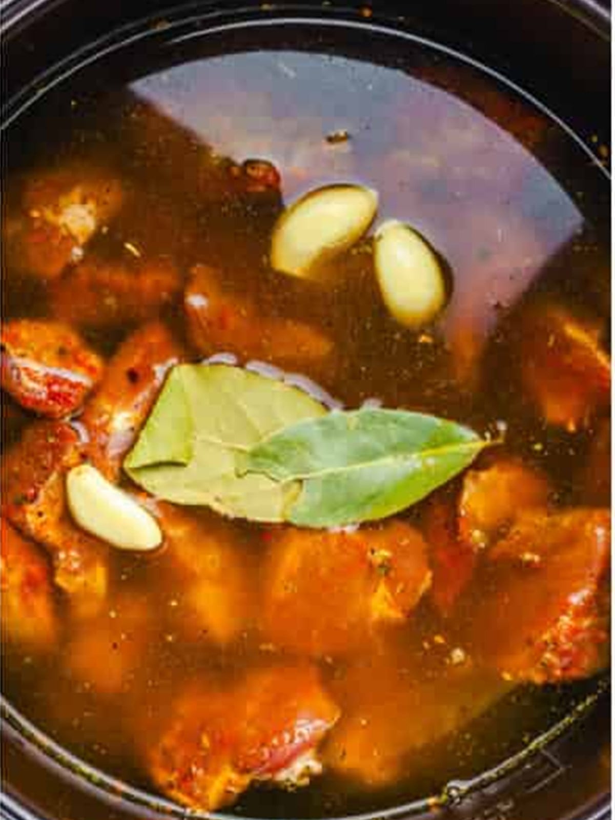 Beef covered with stock in a slow cooker for french dip