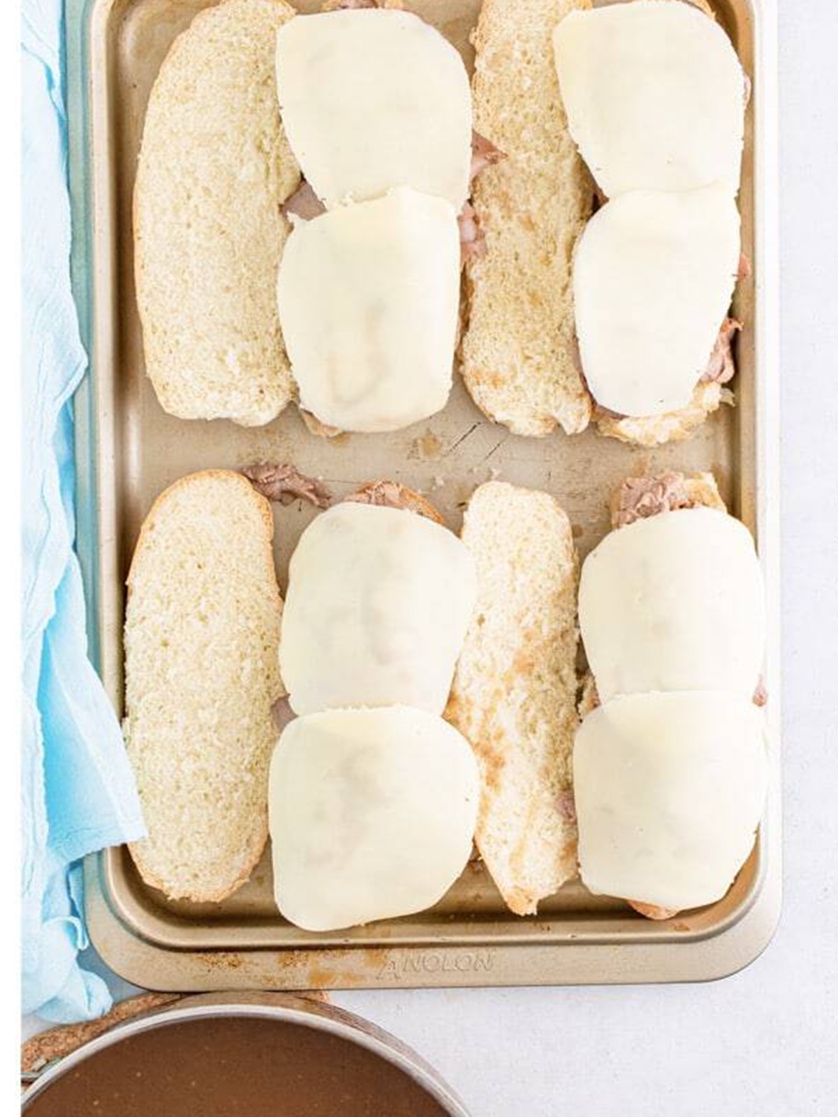 Slices of provolone cheese layered over the roast beef on the rolls.
