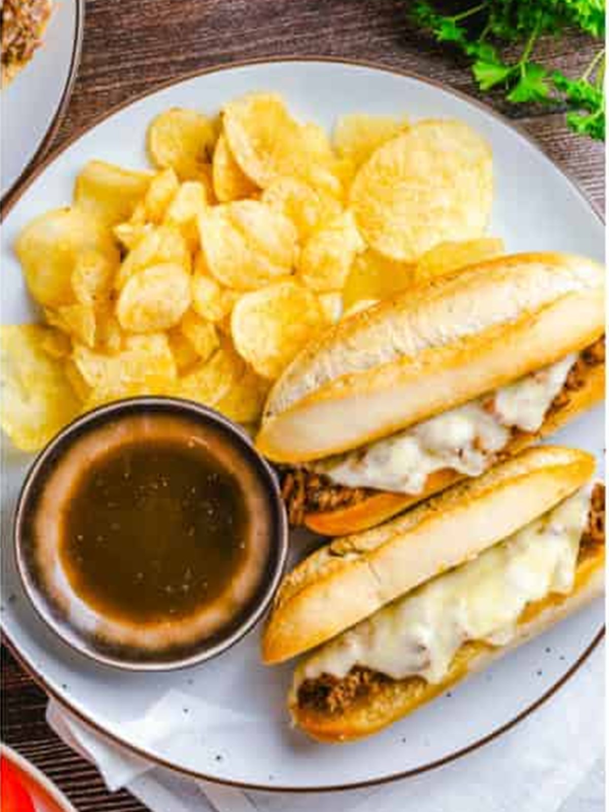 Plated french dip sandwich served with au jus and chips