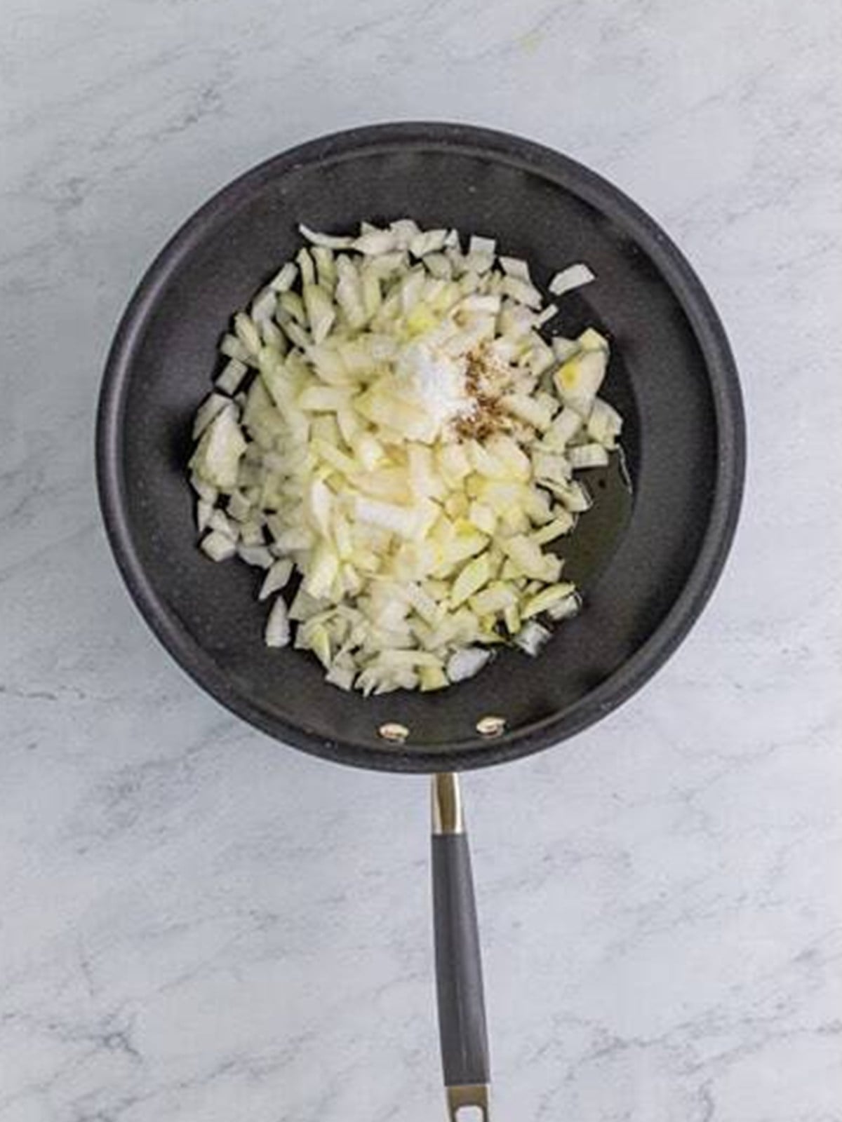 Diced sweet onion cooking in olive oil in a skillet.